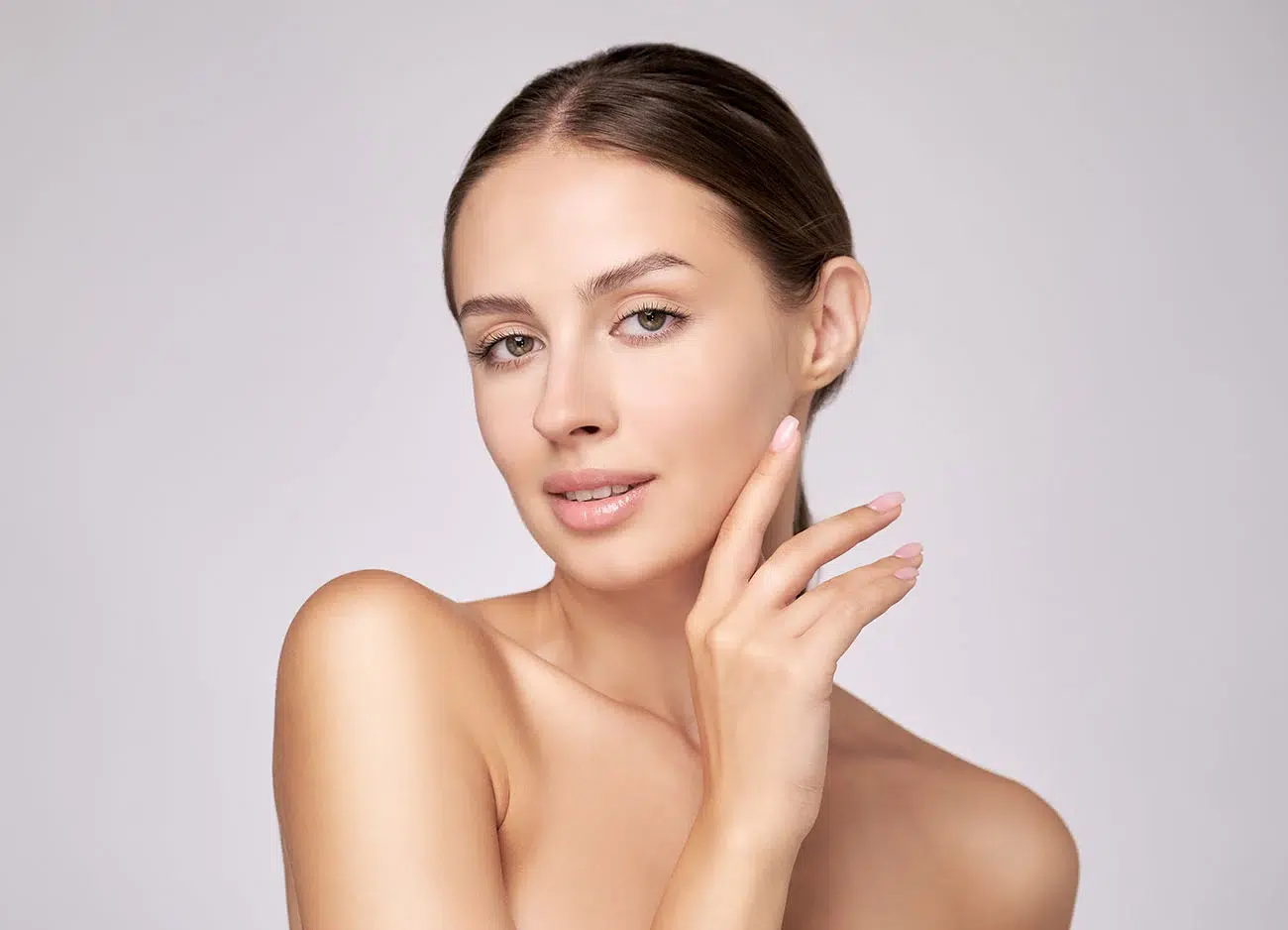 Young woman touching her soft cheek to demonstrate healthy skin after aesthetic facial care. Young woman touching her soft cheek to demonstrate healthy skin after aesthetic facial care.